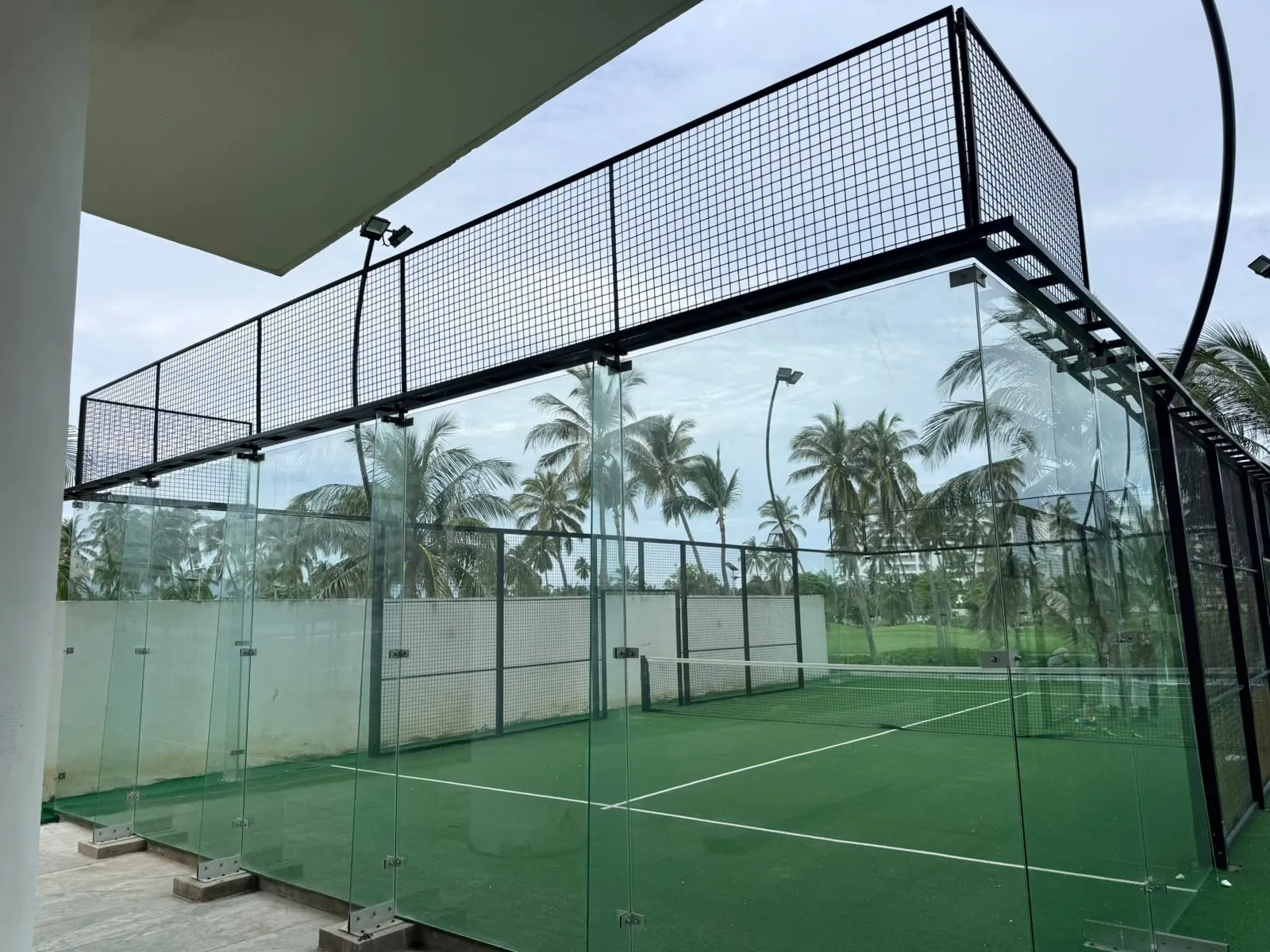 Cinturón perimetral de acero negro con malla sobre cristales templados, cancha de pádel en Acapulco · Padel Center México