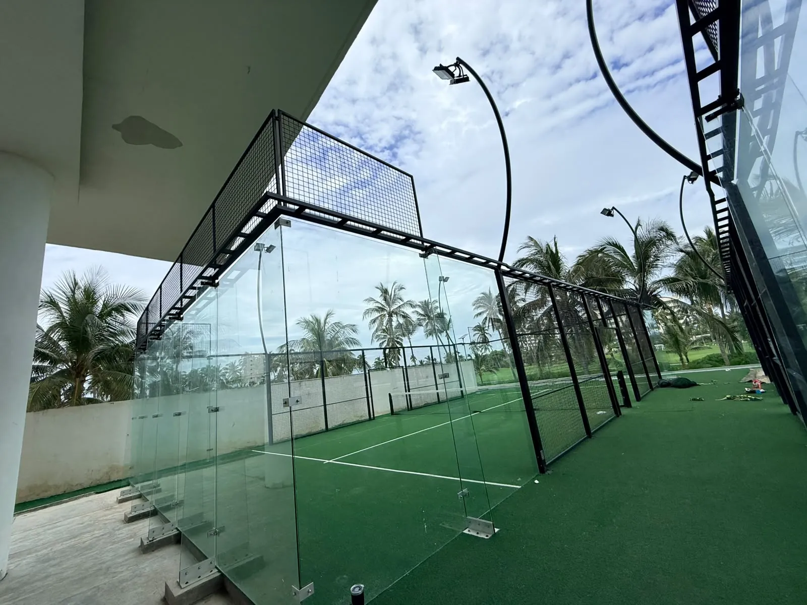Vista desde abajo del cinturón perimetral de una cancha de pádel junto a un edificio en Acapulco
