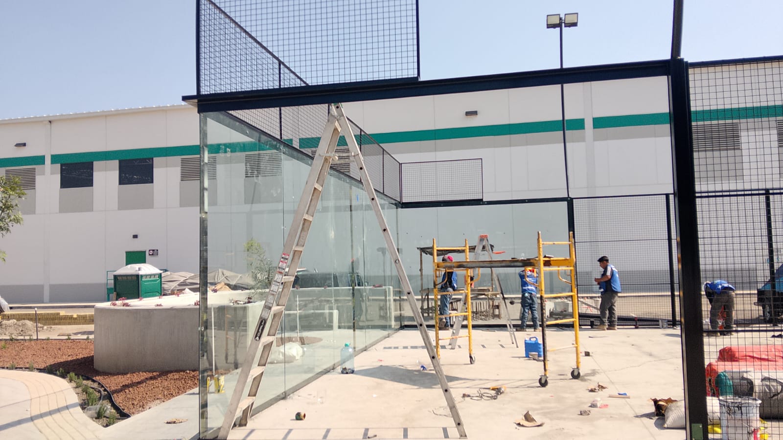 Colocación de cristal templado con escalera en obra de pádel