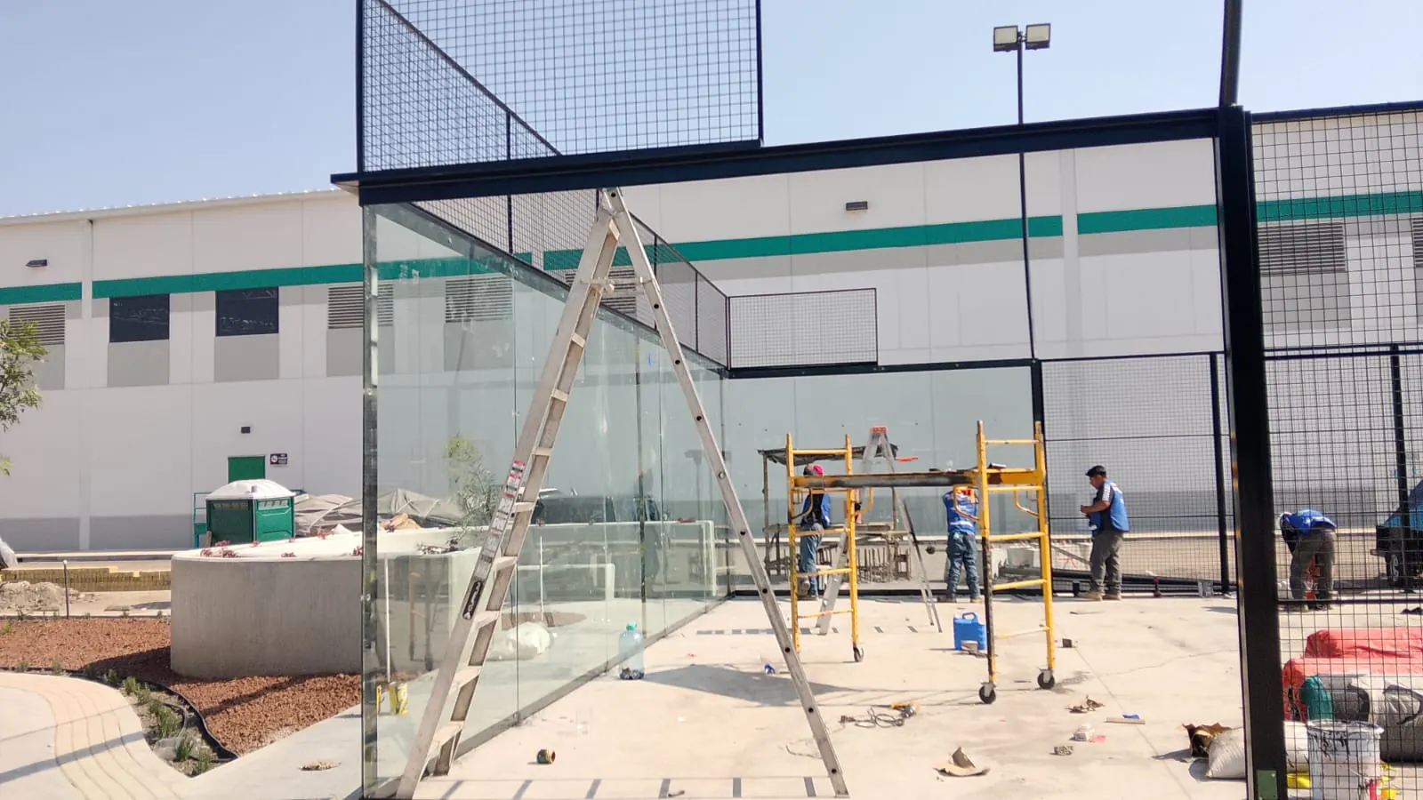 Colocación de cristal templado con escalera en obra de pádel