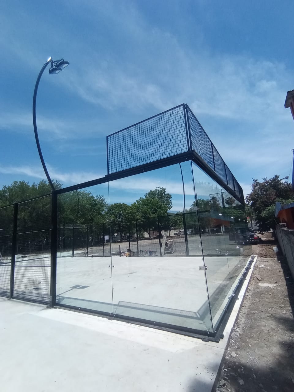 Esquina de cristal templado en cancha de pádel durante montaje