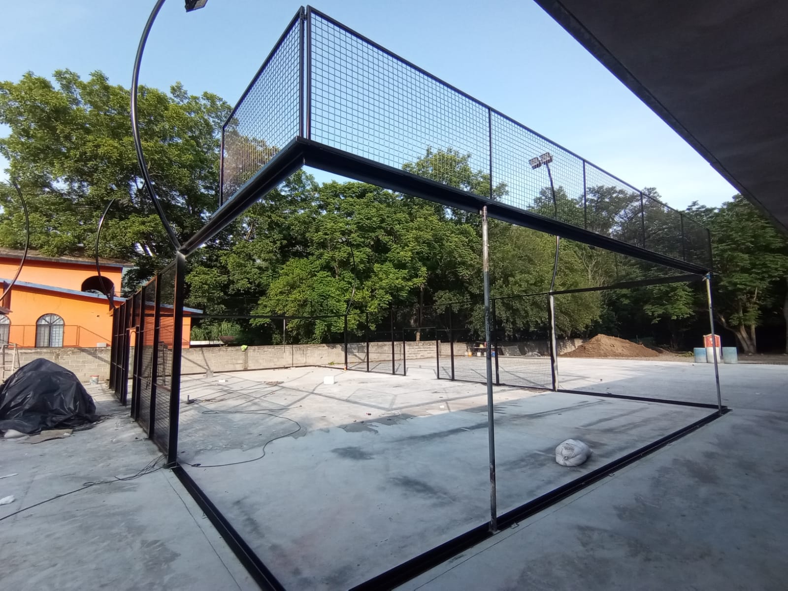 Estructura metálica de cancha de pádel en instalación rodeada de árboles